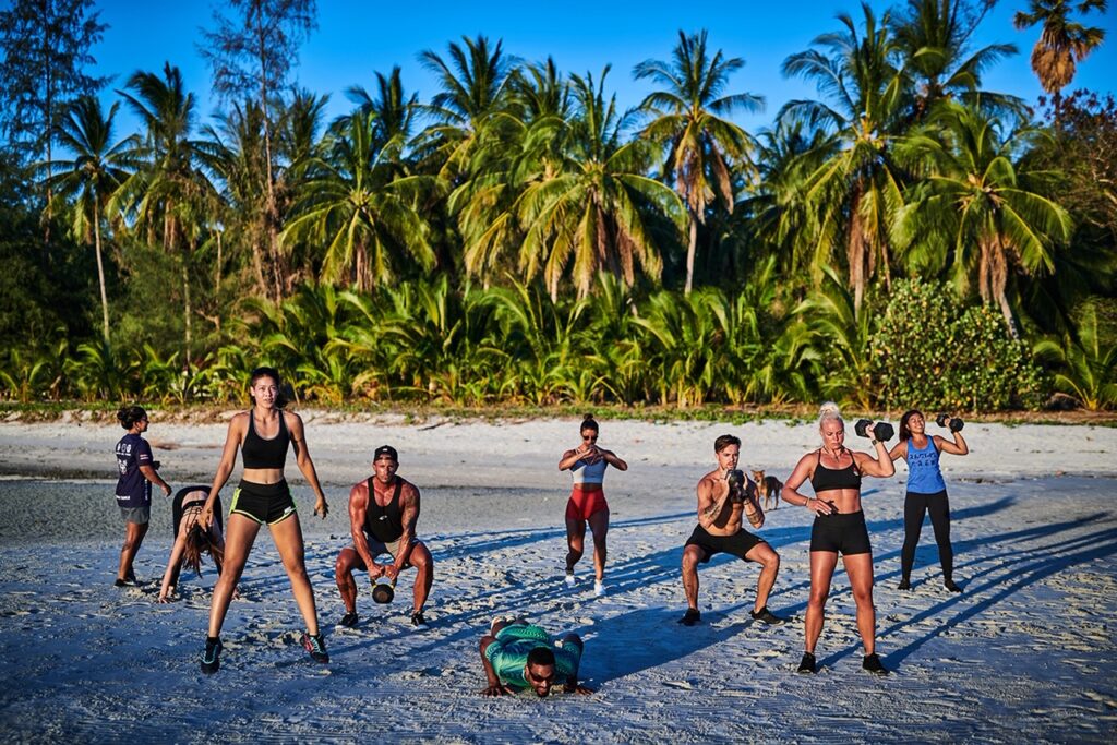 Outdoor group fitness session on the beach under the palms